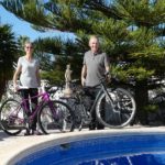Anne-Breivik-og-Kjell-Storerud-med-to-utleiesykler-foran-bassenget-