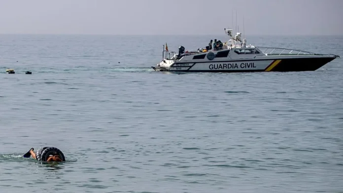 Coast guard patrol boat labeled Guardia Civil on the sea with a swimmer nearby in the foreground.